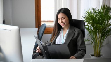 Güzel yönetici bayan yönetici masasındaki dosyada mali belgeyi inceliyor. Ofiste çalışan iş kadını..