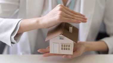 Bir iş kadınının ya da emlakçının güzel bir ev modelini tutarken yakın plan görüntüsü. Emlak yatırım kavramı.