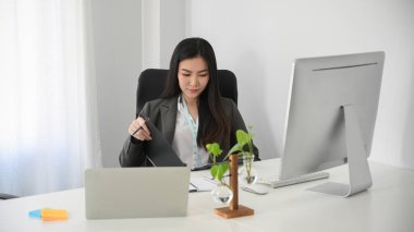 Çekici bayan girişimci bir belgeyi tekrar kontrol ediyor ve ofis masasındaki klasörde bir iş sözleşmesi imzalıyor..