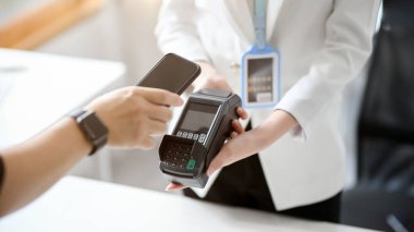 Faturalarını akıllı telefondan ödeme terminaliyle ödeyen bir adamın yakın plan görüntüsü. Dijital cüzdan servisi, mobil bankacılık, QR kod taraması.