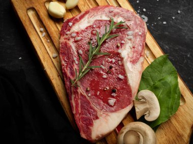 Çiğ bifteğin en üst görüntüsü. Ahşap bir tahtanın üzerinde, siyah taştan bir arka planda..