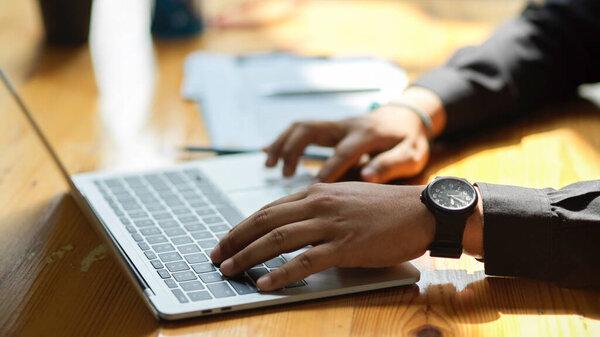 Cropped image of a businessman's hands typing on laptop keyboard at his office desk. searching, browsing internet, working online.