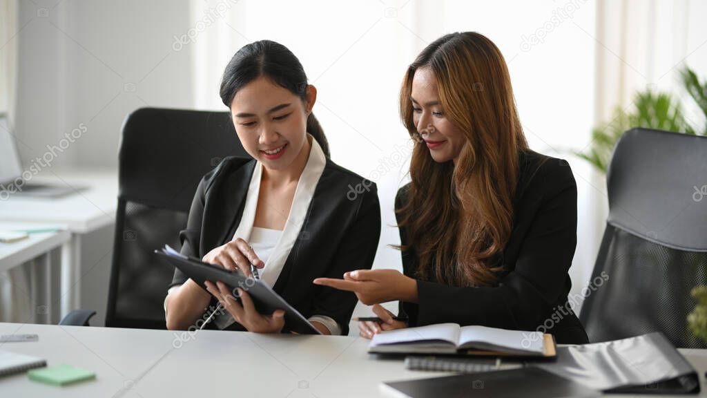 Businesswomen looking at the tablet screen together, discussing marketing plans for the business.