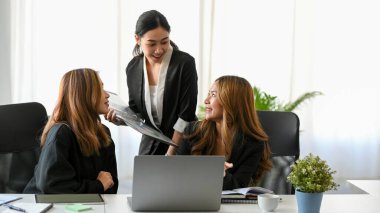 An Asian young businesswomen having a nice conversation at their workplace. A group of marketing team working and discussing in the office.