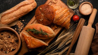 Top view of Delicious organic healthy baked bread on a wooden plate with a cup of grains. Puff, bagel, croissant and baked bun.