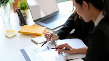 Close-up, A female financial boss briefing an assignment to her employee at office desk.