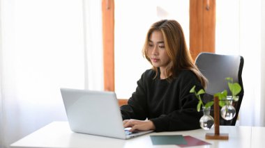 An asian young female college student doing an online test on her notebook computer at her home.