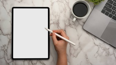 Yakın plan, mermer çalışma alanı üzerinde dijital tablet dokunmatik bilgisayarında stilus kalem kullanan bir kadının üst görünümü.