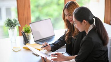 A professional marketing female manager checking her employee's work at her modern office workplace.