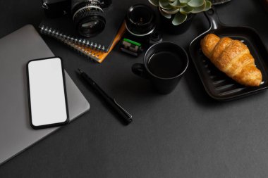 Black office desk background with office supplies, devices and smartphone blank screen mockup.