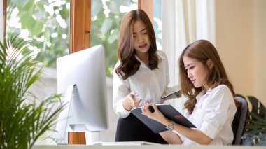 Çekici Asyalı genç iş adamı modern ofis çalışma istasyonunda birlikte çalışıyor. Meslektaşlar, iş arkadaşı konsepti