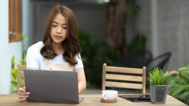 Genç bir bayan dizüstü bilgisayar kullanıyor, online ödev üzerinde çalışıyor, evinin arka bahçesinde defter bilgisayarında sörf yapıyor..