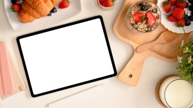 Pasta konseptiyle kadınsı çalışma alanı, tablet boş ekran maketi ve lezzetli hamur işleri. en üstteki görünüm