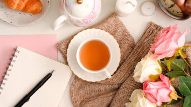 Kadınsı çalışma alanı konsepti, bir defter ya da bir defter, öğleden sonra çayı ve çiçek süslemeleri içeren bir defter. en üstteki görünüm