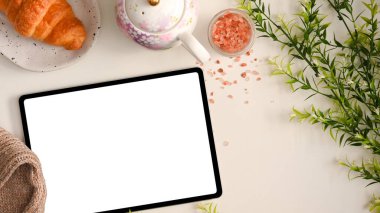 Kadınsı çalışma alanı konsepti, beyaz ekranlı dijital tablet bilgisayar öğleden sonra çay setli güzel çalışma alanı.