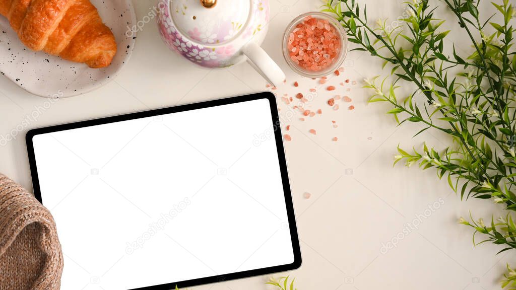 Feminine workspace concept, Digital tablet computer with white screen display on beautiful workspace with afternoon tea set.