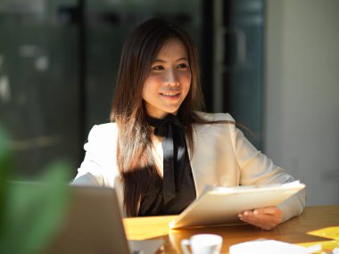 Güzel bayan yönetici ofisinde oturuyor ve proje raporu üzerinde çalışıyor. Asyalı iş kadını kavramı