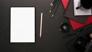 Dijital tablet maketi, kahve fincanı, kırtasiye ve malzeme ile siyah tablo arka planının üst görünümü, kırpma yolunu içerir