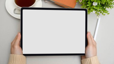 Üst görünüm, modern çalışma alanı üzerinde dijital tablet bir bilgisayarı tutan kadın elleri. tablet boş ekran.