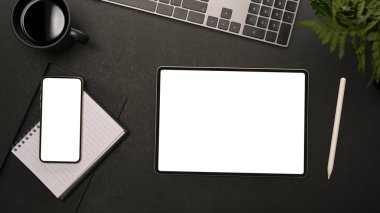 Modern siyah ofis masa arkası malzeme, akıllı telefon ve dijital tablet beyaz ekran görüntüsü. Üst görünüm, düz uzanma