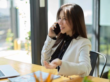Çekici bir Asyalı kadın yöneticinin cep telefonunda bir iş anlaşması var. Telefonda konuşan kadın..