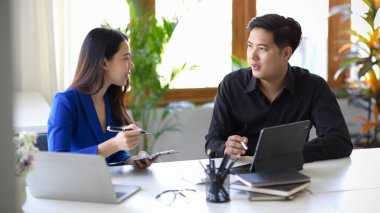 İki Asyalı iş arkadaşı ofiste küçük bir konuşma yapıyor ve iş projelerini tartışıyorlar..