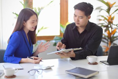 Neşeli bayan yönetici ve erkek asistanı modern ofisin iş planına danışıyorlar. Toplantı, eğitim, danışmanlık, tartışma.