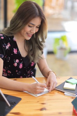 Not defterine liste yapan güzel bir üniversite öğrencisinin portresi, kafenin çalışma yerinde oturuyor..