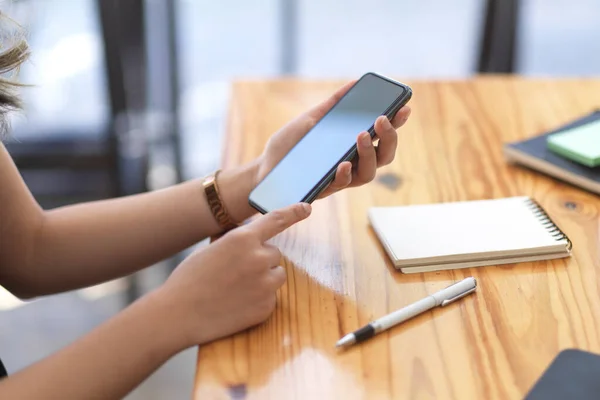 クローズアップショット 木製のテーブルの上にスマートフォンを保持する女性 ソーシャルネットワークメッセージチャットインターネットの閲覧 — ストック写真