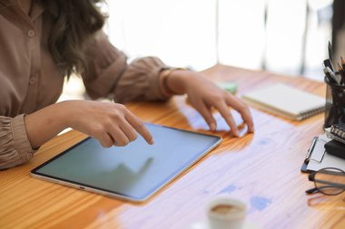 Kesilmiş ve yakın plan görüntü, ofis masasının üzerinde dijital tablet dokunmatik ped kullanan bir kadın..