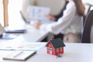 Ofisteki masada bir ev modeli. Emlak yatırımı, emlak ajansı, ev sigortası, emlakçı, komisyoncu konsepti.