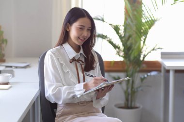 Güzel bir bayan yönetici ofiste belgeyi imzalıyor. Onay, anlaşma, anlaşma ve sözleşme konsepti