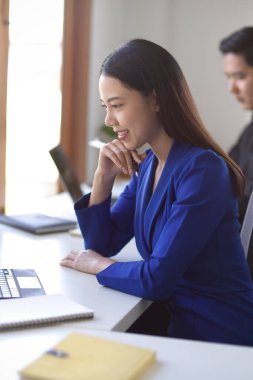 Yan bakış, başarılı Asyalı bir iş kadınının portresi şık takım elbiseli, masasında oturuyor, dizüstü bilgisayar üzerinde çalışıyor ve yeni bir iş fikri düşünüyor..
