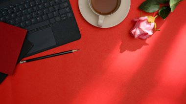 Tabletli kırmızı ofis masası, kahve fincanı, defter, kalem, gül ve fotokopi alanı. en üstteki görünüm