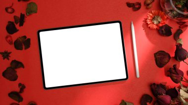 Gül yapraklarıyla süslü kırmızı çalışma alanı ve grafik görüntülerinizi göstermek için dijital tablet bilgisayarın bir maketi. en üstteki görünüm