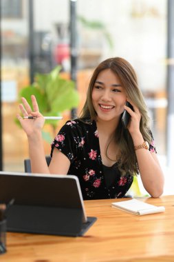 Portre, güzel Asyalı kadın gülümseyerek uzaktaki birine bakarken cep telefonuyla konuşuyor..