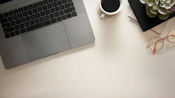 Modern home office desk workspace with laptop, glasses, coffee cup, copy space, sunlight shadows on white background. Flat lay, top view