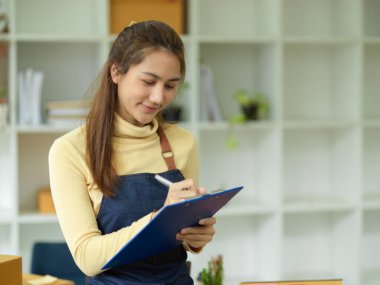 Güzel bir Asyalı genç bayan iş kurumu müşteri siparişlerini panoya yazıyor. E-ticaret işadamları.