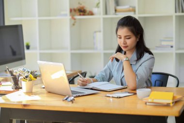 Profesyonel Asyalı kadın patron yeni iş stratejisi raporunu kontrol ediyor, kampanyasını planlıyor, ofiste çalışıyor..