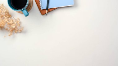 Kurumuş çiçek, kahve fincanı, not defterleri ve ürün sergisi veya arkaplan sunumuyla basit beyaz çalışma alanı. en üstteki görünüm