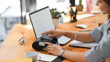 Çekici bir kadın bankacı ofis masasındaki ödeme terminali makinesinden kredi kartı çalıyor. irtibatsız teknoloji, şehir yaşam tarzı.