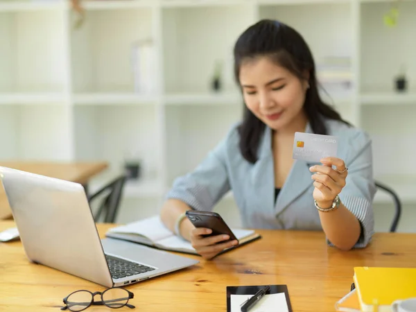 一名亚洲成年女商人用手机申请支付账单 并在网上银行申请表上键入她的信用卡号码 — 图库照片