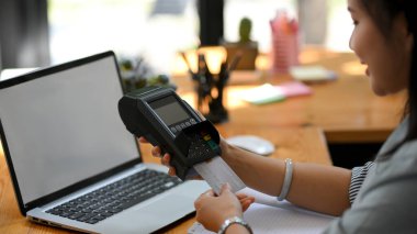 Yakın plan, kadın bir otel resepsiyonisti müşterinin faturasını ödemek için kredi kartı takıyor. elektronik cüzdan ödemesi