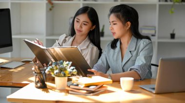 İş kadını, ofiste takım çalışması yapan iş arkadaşına iş fikrini açıklar ve paylaşır..