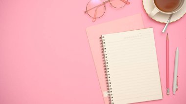 Mesajınız, gözlükleriniz, çay fincanınız, kalemleriniz ve pembe arkaplanınızdaki fotokopi alanınız için küçük ofis masası. Üst görünüm, düz uzanma