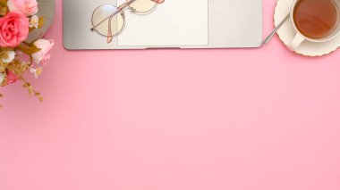 Genel çekim, modern ofis çalışma alanı dizüstü bilgisayarı, çay fincanı, gözlük, çiçekler ve kopyalama alanı olan.