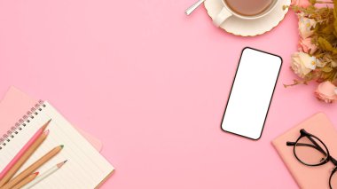 Akıllı telefon beyaz ekran modeli, ofis aksesuarları ve pembe arka planda kopyalama alanı olan pembe bir ofis masası çalışma alanı. en üstteki görünüm 