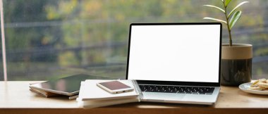 Tablet, akıllı telefon ve portatif kafe çalışma alanında aksesuarlı laptop beyaz ekran modeli. Elektronik cihazlar masada. uzak çalışıyor