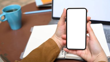 Yakın plan görüntü, masasının üzerinde cep telefonu beyaz ekran modeli tutan bir kadın. internet bağlantısı, mobil uygulama.