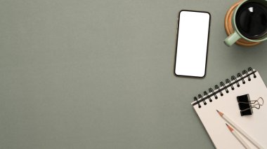 Çalışma alanındaki alanı montaj için kopyalayın. Akıllı telefon boş ekran maketi, kahve fincanı ve kırtasiye malzemesi ile gri arkaplan üzerinde ürün veya metin görüntüsü. Üst görünüm, düz uzanma